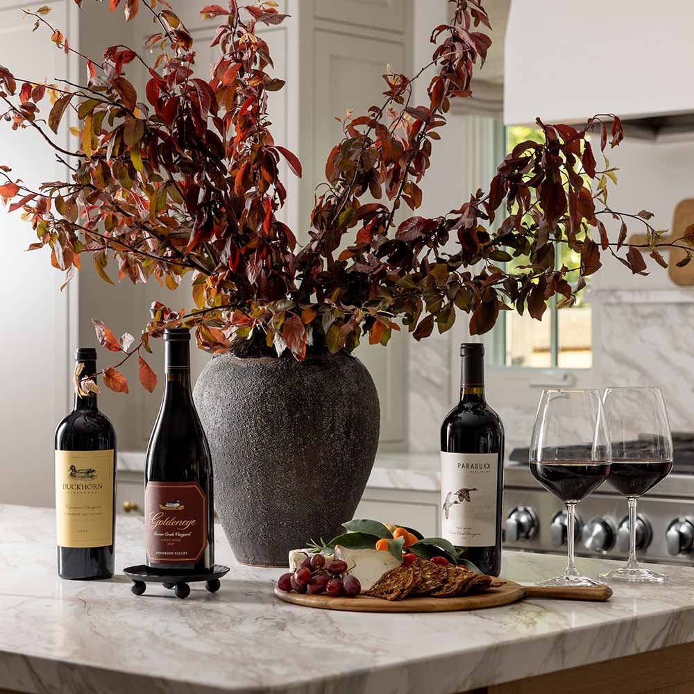 Red wines in a kitchen with fall foliage